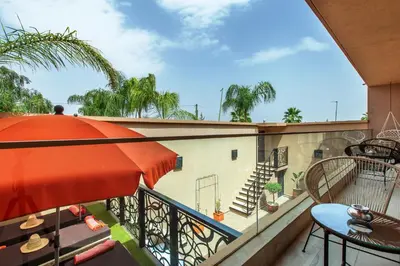 a balcony with an orange umbrella and a table and chairs at Villa Serenity & SPA - Breakfast in Marrakech