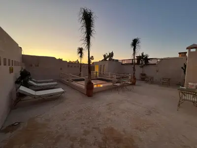 a patio with palm trees and tables and a sunset at Riad Darchica in Marrakech