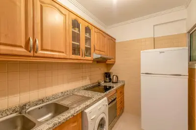 a kitchen with wooden cabinets and a white refrigerator at Central Cosy Appartement Avec Piscine in Marrakech