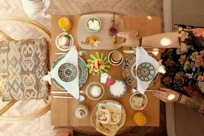 a woman sitting at a table with plates of food at Riad BE Marrakech in Marrakech