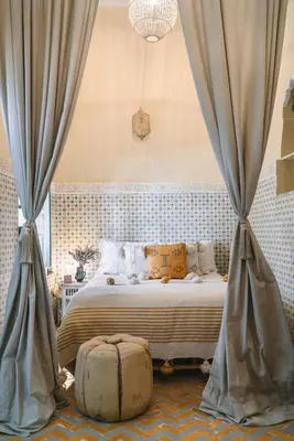 a bedroom with a bed with curtains and a suitcase at Riad BE Marrakech in Marrakech