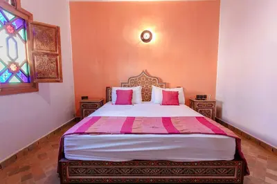 a bedroom with a bed with pink pillows and a window at Riad Tranquility - A Timeless Marrakech Haven in Marrakech