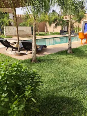 a swimming pool with a bench and trees in a yard at Riad Safran Ralya in Marrakech
