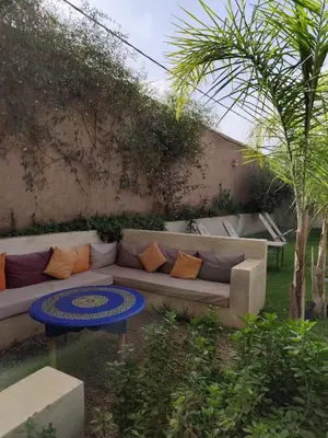 a couch with pillows on it in a garden at Riad Safran Ralya in Marrakech