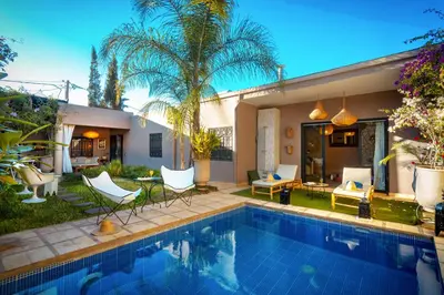 a swimming pool with chairs and a house at Villa Cosy Piscine Proche centre-ville 4 suites in Marrakech
