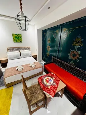a bedroom with two beds and a red bench at Riad hotel Cecil in Marrakech
