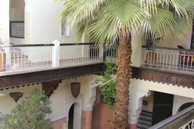a palm tree next to a building with balconies at Riad Jnan El Cadi in Marrakech
