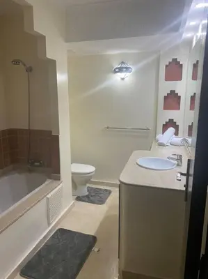 a bathroom with a sink and a tub and a toilet at Appartement Ensoleillé vue Piscine in Marrakech