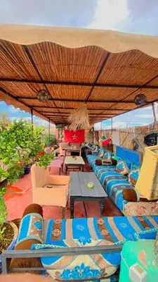 a group of chairs and tables under an umbrella at Hostel kif kif annex in Marrakech