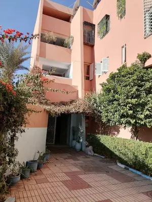 a pink building with a courtyard with plants at Julie's AIRPORT Apartment in Marrakech
