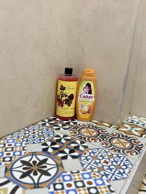 a bottle of cleaning agent and a container of cleaner on a bathroom floor at Julie's AIRPORT Apartment in Marrakech