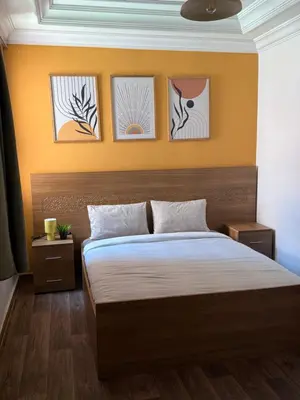 a bedroom with a bed with four pictures on the wall at Julie's AIRPORT Apartment in Marrakech