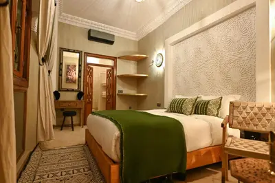 a bedroom with a bed with a green blanket on it at Riad Chez Henriette in Marrakech