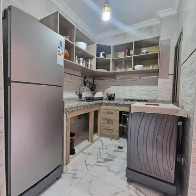 a kitchen with a white refrigerator and marble floors at Bel appartement de 2 chambres M in Marrakech