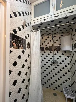 a bathroom with a shower with a black and white wall at Charmant Appartement 2 Chambres pour Sejours en Famille Marrakech in Marrakech