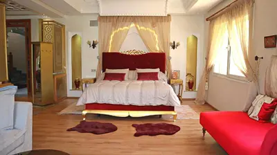 a bedroom with a bed and a red couch at Barthélemy Guest House in Marrakech