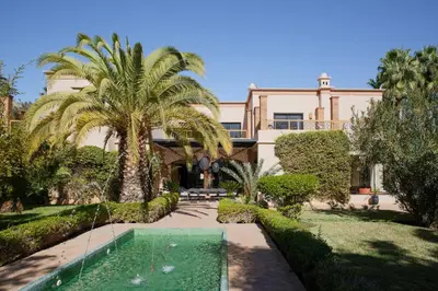 a house with a palm tree and a swimming pool at Maggy Rose in Marrakech