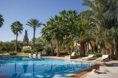 a pool with palm trees and lounge chairs at Maggy Rose in Marrakech