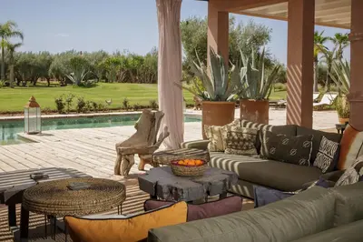 a patio with a couch and tables and a pool at Villa MISH-MISH in Marrakech