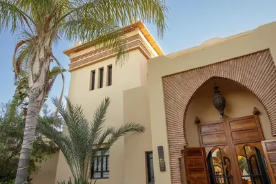 a building with a palm tree next to a door at Dar Banati Palmeraie in Marrakech