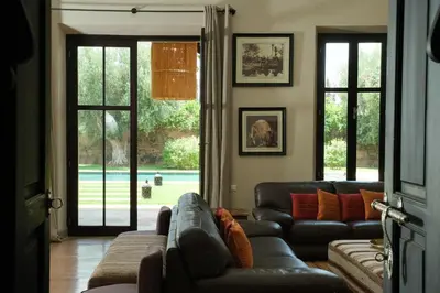 a living room with leather couches and a large window at Villa Jennabelle in Marrakech