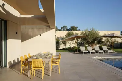a dining table with yellow chairs and a pool at ADA ADA modern villa with heated private pool next city center in Marrakech