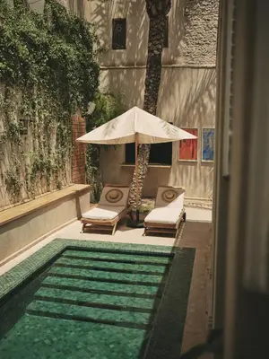 an umbrella and chairs next to a swimming pool at IZZA Marrakech in Marrakech