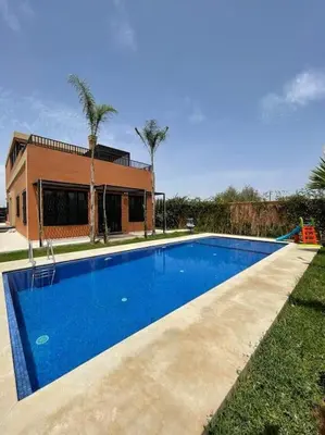a large blue swimming pool in front of a house at Villa Amèle,calme,Ensoleillé,Piscine,Salle de jeux in Marrakech