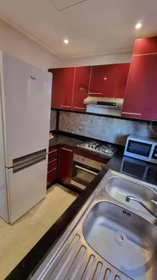 a kitchen with red cabinets and a stainless steel sink at Appartement paisible et abordable Palmeraie Marrakech in Dar Caïd Layadi