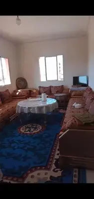 a living room with a table and a blue carpet at Samlalia home in Marrakech