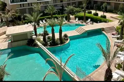 a pool in a resort with palm trees at appartement en résidence in Marrakech