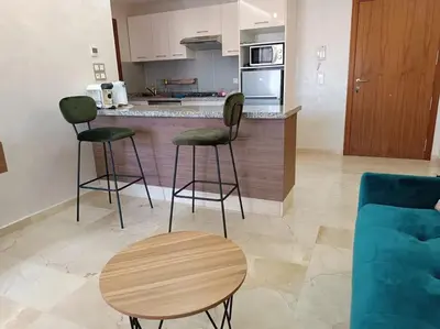 a kitchen with two stools and a table and a couch at appartement en résidence in Marrakech