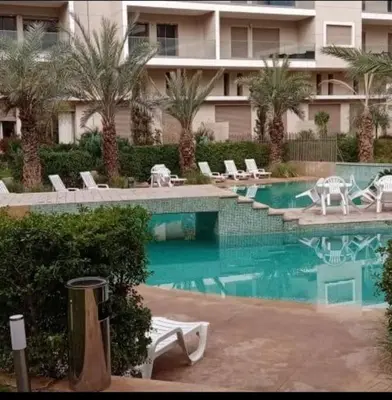a swimming pool with chairs and a building at appartement en résidence in Marrakech