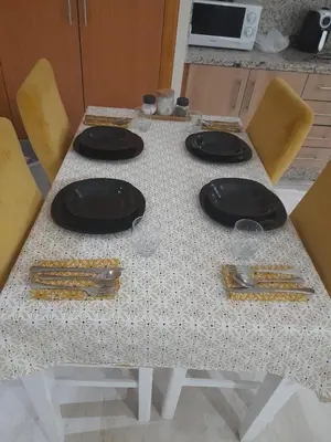 a table with black plates and yellow chairs at appartement génial in Marrakech