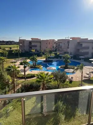 a view of a pool with palm trees and buildings at Beautiful apartment in Golf City Marrakech in Marrakech