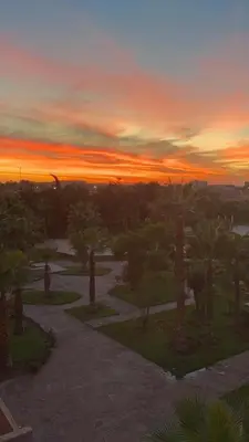 a sunset over a park with trees and a pathway at Appartement Hivernage M Avenue in Marrakech