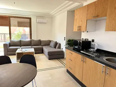 a kitchen and living room with a couch and a table at APPARTEMENT JAWHARA HIVERNAGE in Marrakech