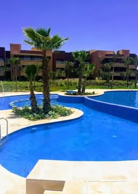 a large blue pool with palm trees in a building at Marrakech Prestigia Golf City - beauty Appartement in Marrakech