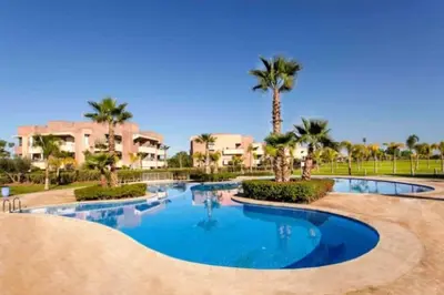 a swimming pool with palm trees in a resort at Marrakech Prestigia Golf City - beauty Appartement in Marrakech