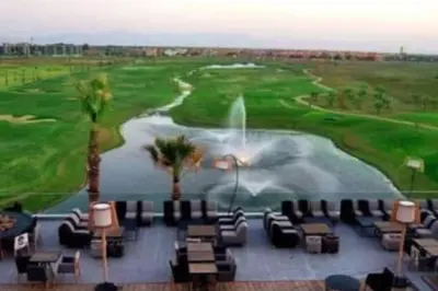 a view of a golf course with chairs and a fountain at Marrakech Prestigia Golf City - beauty Appartement in Marrakech