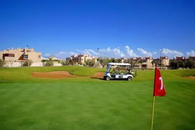 a golf cart on a green with a red flag at Marrakech Prestigia Golf City - beauty Appartement in Marrakech