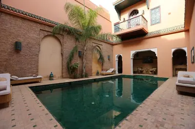 a swimming pool in a courtyard with a house at Palais Riad Lamrani in Marrakech