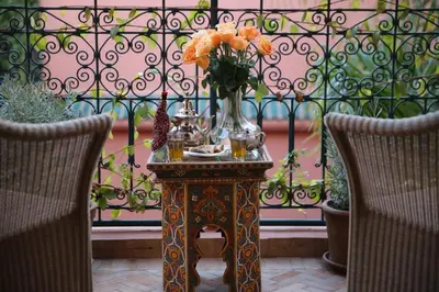 a table with a vase of flowers on it with two chairs at Palais Riad Lamrani in Marrakech