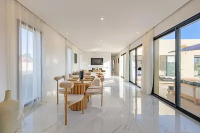 a dining room with a table and chairs and windows at Villa Victoria, piscine Chauffée, sans vis à vis in Marrakech