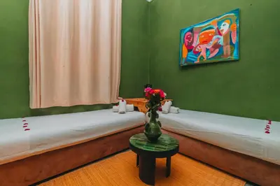 two beds in a room with a vase of flowers on a table at Hotel & Riad Veridis in Marrakech