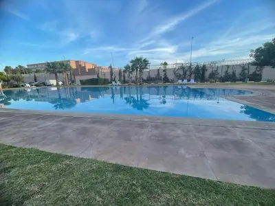 a pool of blue water in a parking lot at Appartement Coralia in Marrakech
