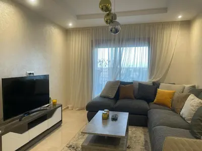 a living room with a couch and a flat screen tv at Appartement Coralia in Marrakech