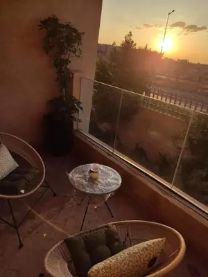 a balcony with a table and chairs in front of a window at Appartement Coralia in Marrakech