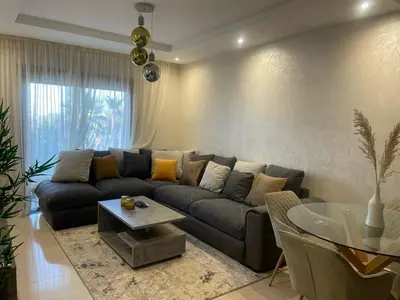 a living room with a couch and a glass table at Appartement Coralia in Marrakech