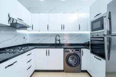 a white kitchen with a washing machine and a microwave at Les Palmier de targa, Romantic appartement in Marrakech